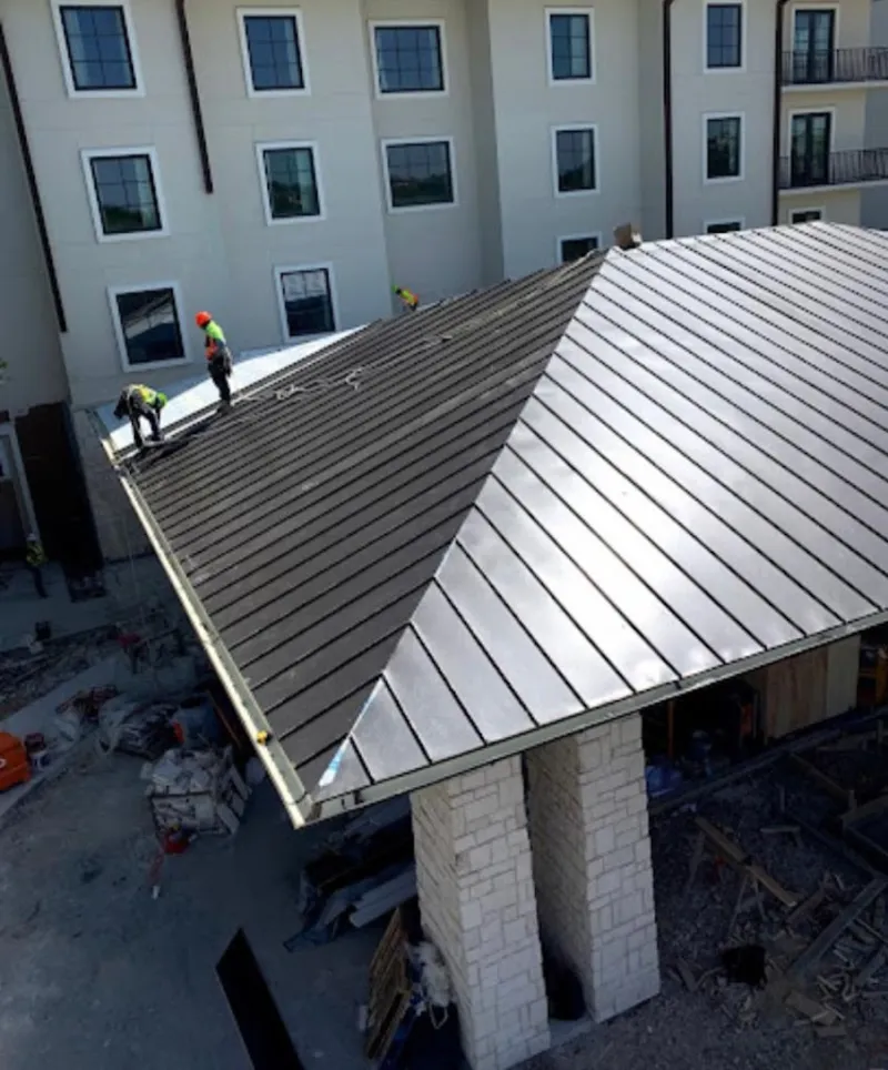 Crew installing standing seam metal roof panels on a commercial project in Hapeville